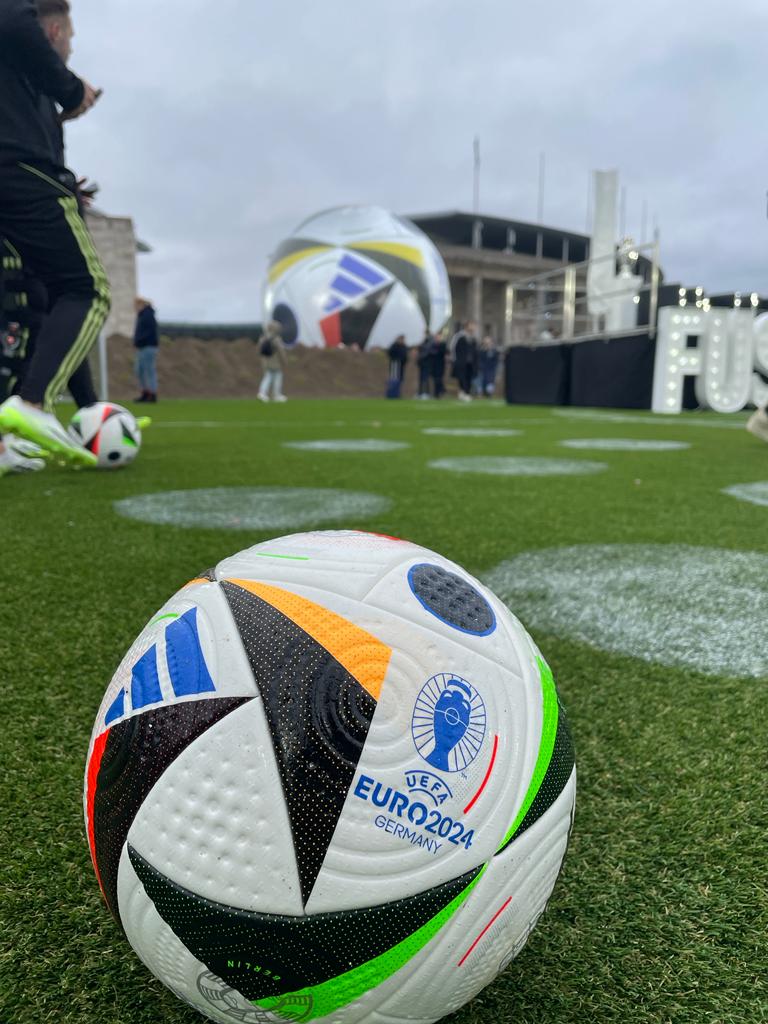 adidas Ball mit Namen Fussballliebe auf grünem Rasen vo dem Olympiastadion